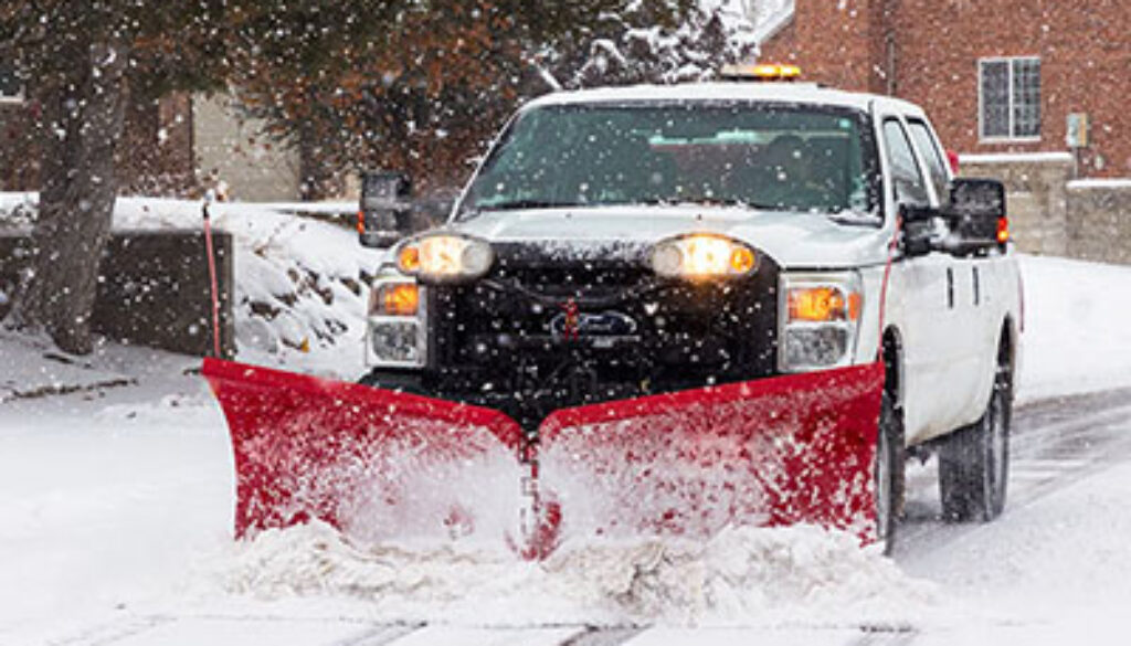 front image of white pickup truck with red snow plow on a snowy street